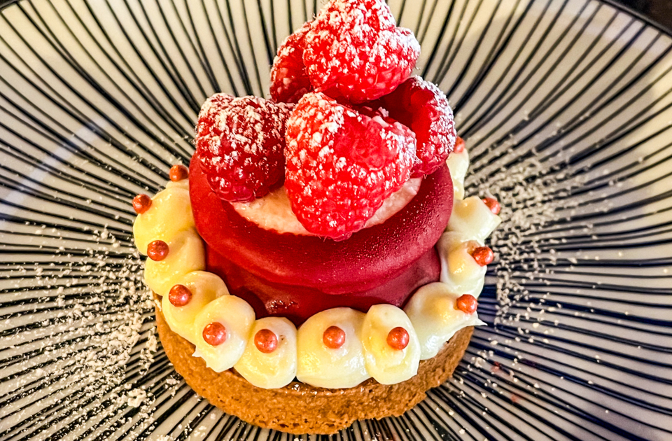 Berry Cute dessert at Incanto, featuring a creamy vanilla cheesecake layer topped with fresh raspberries, on a rich chocolate base.