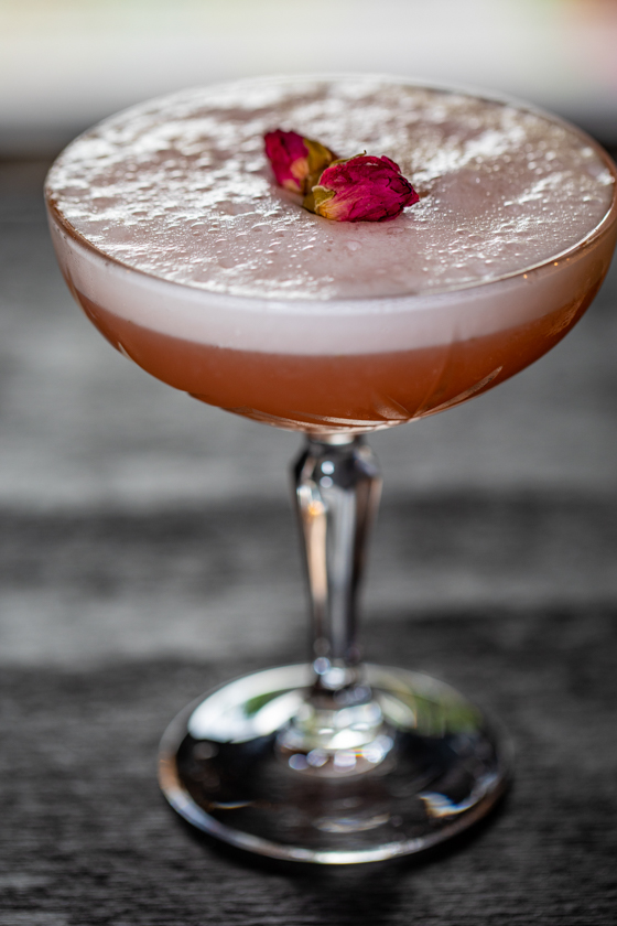 A beautifully crafted "Rosalina" cocktail at Incanto in The Heights, Houston, featuring Tito’s Vodka, St. Germain, strawberry, lemon juice, rosewater, and a frothy egg white top.